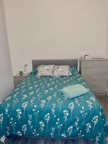 a bed with a blue blanket with white flowers at Family House in Liverpool