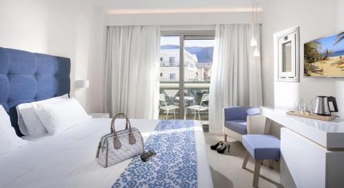 a hotel room with a large bed and a desk and atains sidx sidx sidx at Petra Beach Hotel in Hersonissos