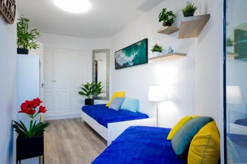 een slaapkamer met 2 bedden met blauwe en gele kussens bij GP127 apartman Tenerife in San Miguel de Abona