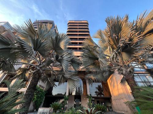 a tall building with palm trees in front of it at Flat Ipanema - Vieira Souto 500 in Rio de Janeiro