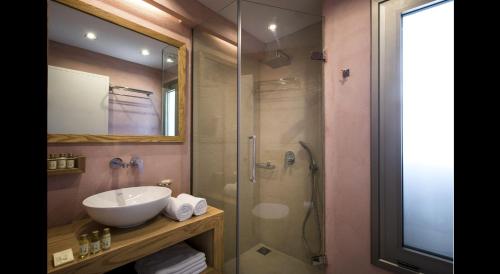 a bathroom with a sink and a glass shower at Petra Beach Hotel in Hersonissos