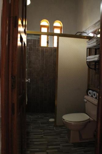 a bathroom with a toilet and a shower with two windows at Bungalows Las Tortugas in Lo de Marcos
