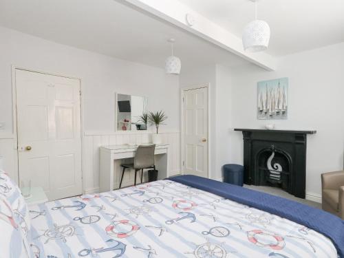 une chambre blanche avec un lit et un bureau dans l'établissement Harbour Tales, à Weymouth