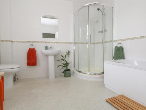 une salle de bain blanche avec une douche et un lavabo dans l'établissement Harbour Tales, à Weymouth