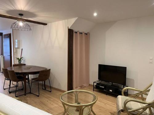 a living room with a table and a television at Chez SAM in Langres