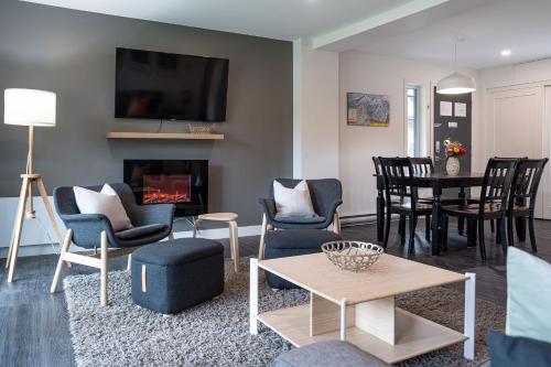 a living room with a fireplace and chairs and a table at Granite Ridge Condo by Revelstoke Vacations in Revelstoke