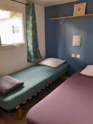 une petite chambre avec deux lits et une fenêtre dans l'établissement Location Mobil home Camping Pédro, au Grau-dʼAgde