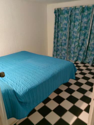 a bedroom with a blue bed and a checkered floor at Vacacional Luna Mar in Rincon de Guayabitos
