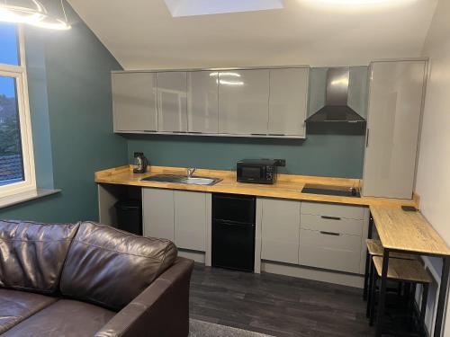 a kitchen with a counter and a couch in a room at Welcome to your stay The Nest in Bolton