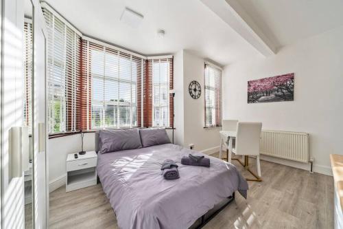 - une chambre avec un lit, un bureau et des fenêtres dans l'établissement Charming Flat In Shepherds Bush, à Londres