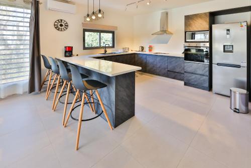 a kitchen with white tile flooring and a large island with bar chairs at OceanBreeze Apartments Mont Choisy in Mont Choisy