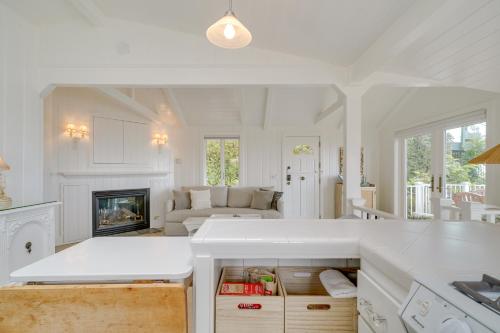 a white kitchen with a living room with a fireplace at Stunning Ventura Cottage with Deck and Ocean View! in Ventura