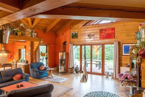 a large living room with orange walls and wooden ceilings at Ptasi Dom — Saunowisko w Kępie in Świeszyno