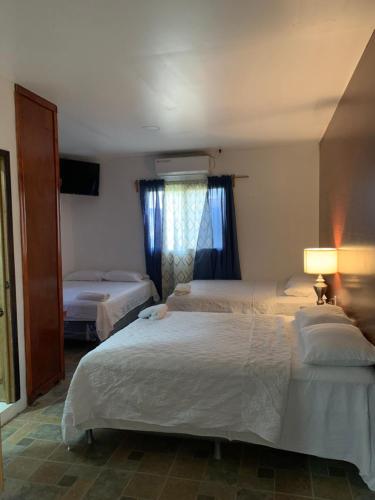 a hotel room with two beds and a window at Complejo Deportivo Wilson Palacios in La Ceiba