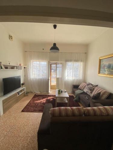 Homey Apt. with beautiful view في عمّان: غرفة معيشة مع أريكة وتلفزيون