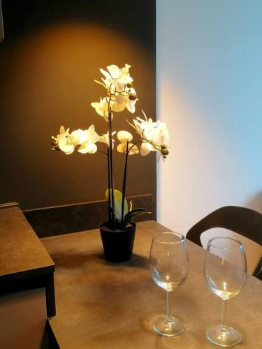 a table with two wine glasses and a vase with white flowers at Monolocale Niki - Holiday Home in Trento