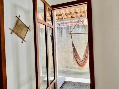 una puerta de cristal con una hamaca en una habitación en Casa com quintal, en Arraial d'Ajuda