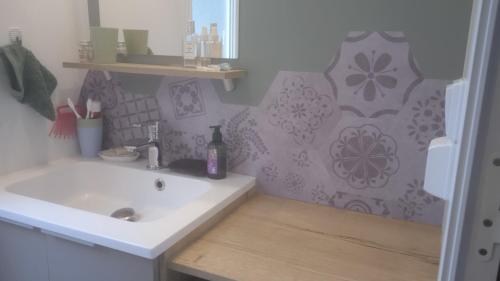 La salle de bains est pourvue d'un lavabo blanc et d'un mur violet. dans l'établissement Kerlann, à Pont-Aven