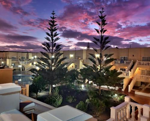 a view of a resort with palm trees at dusk at 'Casa Ideal' A22 - Las Arenas Complex in Caleta De Fuste
