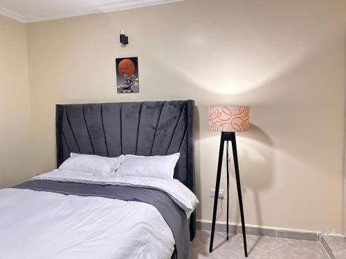 a bedroom with a bed with a black headboard and a lamp at Luxurious 2 bedroom penthouse-Fully Furnished at 360 Luxury in Kitale