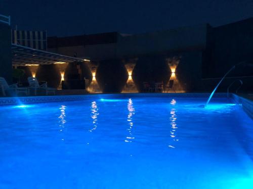 a swimming pool at night with blue lights at Cali Chalet in Al Karāmah