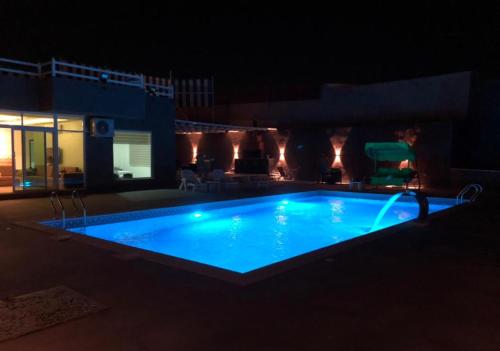 a swimming pool lit up at night at Cali Chalet in Al Karāmah