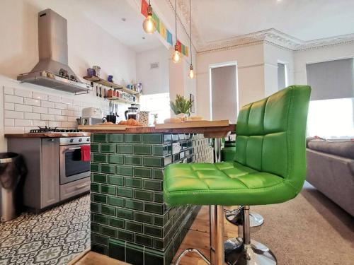 a green chair in a kitchen with a counter at Church Retreat - A Magnificent Sea Side Apartment in Hastings