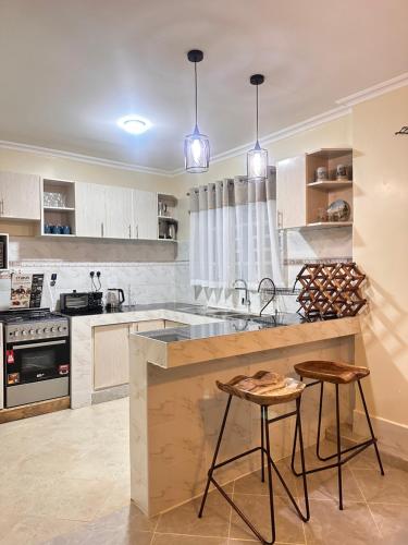 a kitchen with a sink and a counter with two stools at Exquisite two bedroom Penthouse-Fully Furnished in Kitale