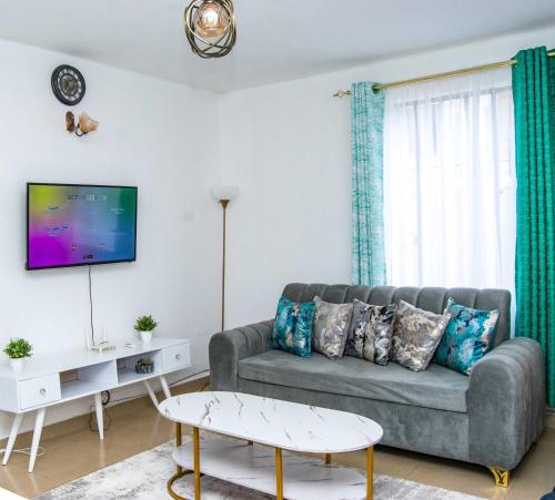 Una sala de estar con un sofá y un televisor. en Tina's cosy 2br : Wi-fi & Parking in Milimani, en Kisumu
