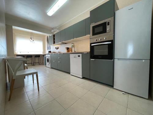 a kitchen with gray cabinets and appliances and a table at MHouse lease Cascais Spacious 3 BR Family next center in Alcabideche