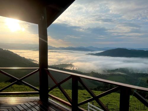 a room with a view of the mountains with clouds at Chalé Pico da Mantiqueira in Sapucaí-Mirim