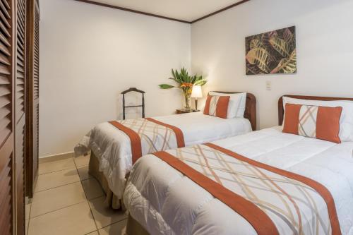 two beds in a room with white walls at Hotel Residence Inn Suites Cristina in San José