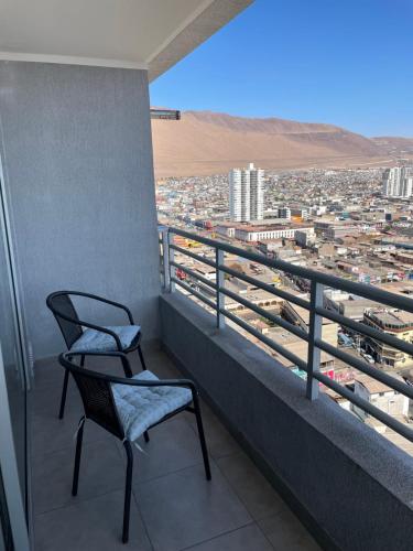 a balcony with two chairs and a view of a city at Cómodo departamento diario céntrico in Iquique