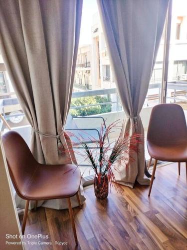 two chairs and a vase with a plant in a window at Central Sophisticated Studio Pyrgos near Olympia in Pýrgos