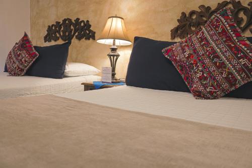 a bedroom with two beds with pillows and a lamp at Hotel Posada de la Luna in Antigua Guatemala