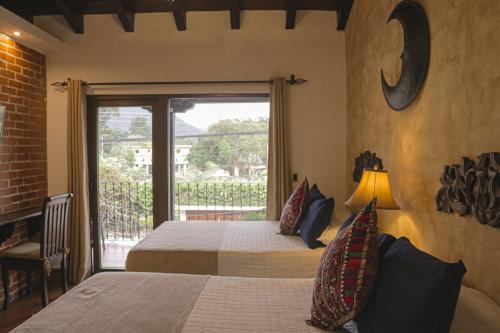 a bedroom with two beds and a door to a balcony at Hotel Posada de la Luna in Antigua Guatemala