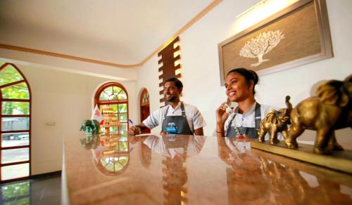 a man and woman sitting at a table with statues of animals at Wisdom Boutique Resort in Kandy