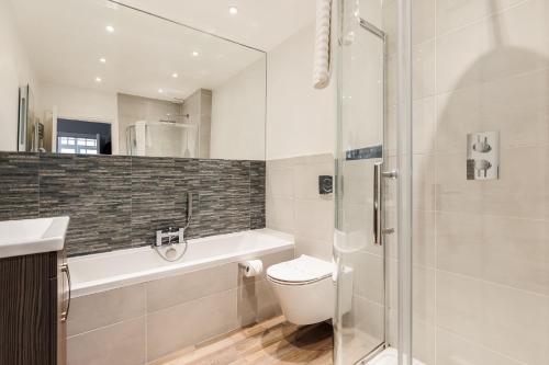 een badkamer met een douche, een toilet en een wastafel bij Cobalt Cove in Poole