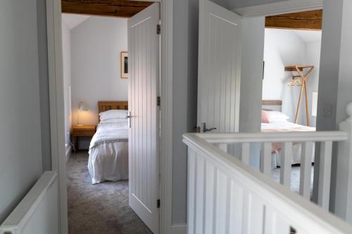 a hallway with a bedroom with a bed and a staircase at La Roche-Barn with hot tub on the Welbeck estate in Holbeck