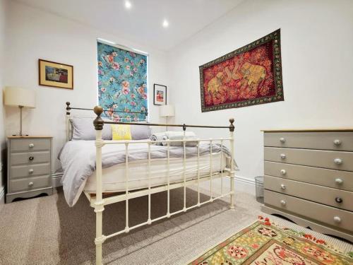 a bedroom with a bed and two dressers at Gensing Lodge - A Beautiful Artistic Maisonette in St. Leonards