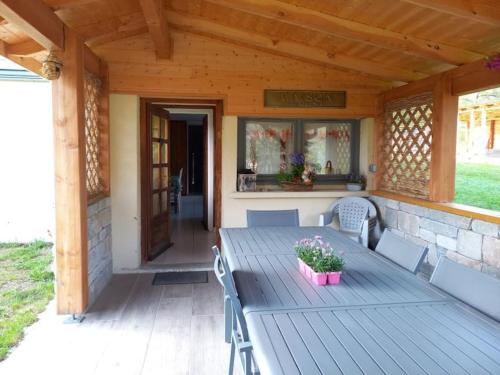 une terrasse couverte en bois avec une table et des chaises en bois dans l'établissement Appartement cosy à Bussang, à Bussang