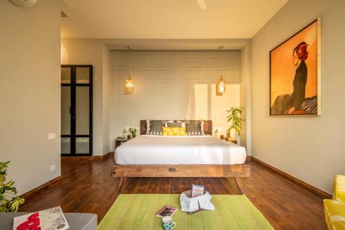 a bedroom with a large white bed and wooden floors at La Viola Estate in Anjuna