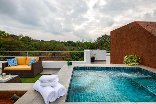 a pool on a patio with a couch and a chair at La Viola, 3BHK Villa with rooftop Jacuzzi, close to Anjuna & Vagator Beach with Private Pool, Kitchen, Terrace in Anjuna