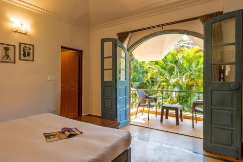 a bedroom with a door open to a balcony at Beachside Bliss Villas Candolim 10 min walk from Sinquerim Beach in Sinquerim