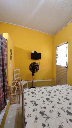 ein Schlafzimmer mit einem Bett und einer gelben Wand in der Unterkunft Quartos simples e aconchegantes na orla de Itaparica in Itaparica Town
