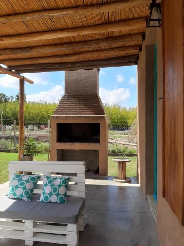 a patio with a fireplace and a bench with pillows at Complejo ROSA OLIVA in Albardón