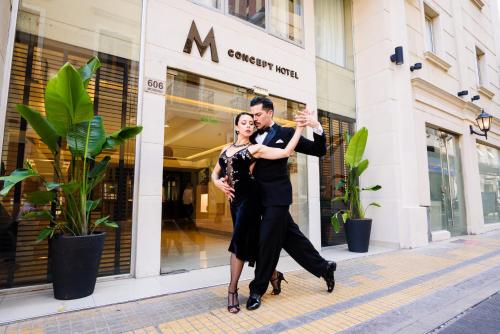 a man and a woman dancing in front of a store at M Concept Hotel in Buenos Aires