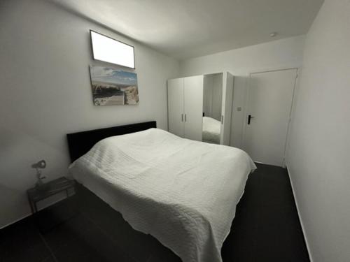 a white bedroom with a bed and a window at Appartement Guillaume in Blankenberge