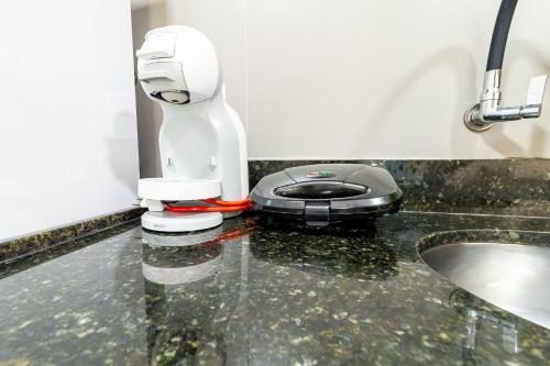 a white robot sitting on a counter next to a sink at Apartamentos com internet rápida in Maceió