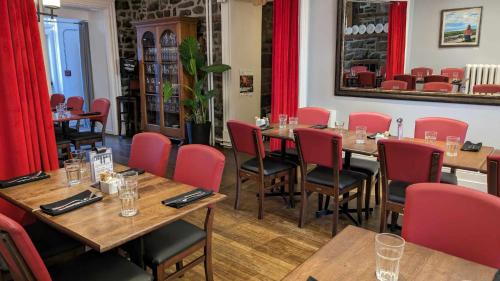 a restaurant with wooden tables and red chairs at La Maison Rousseau in Montmagny